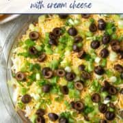 7 layer taco dip with olives and green onions on top.