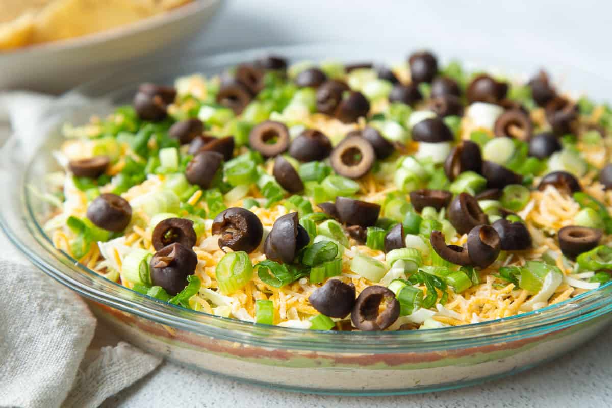 7 layer taco dip with olives and green onions on top.