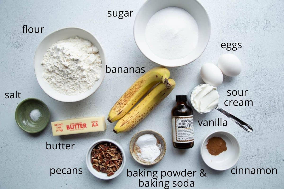 bananas, flour, sugar, sour cream, and other ingredients on a white table.