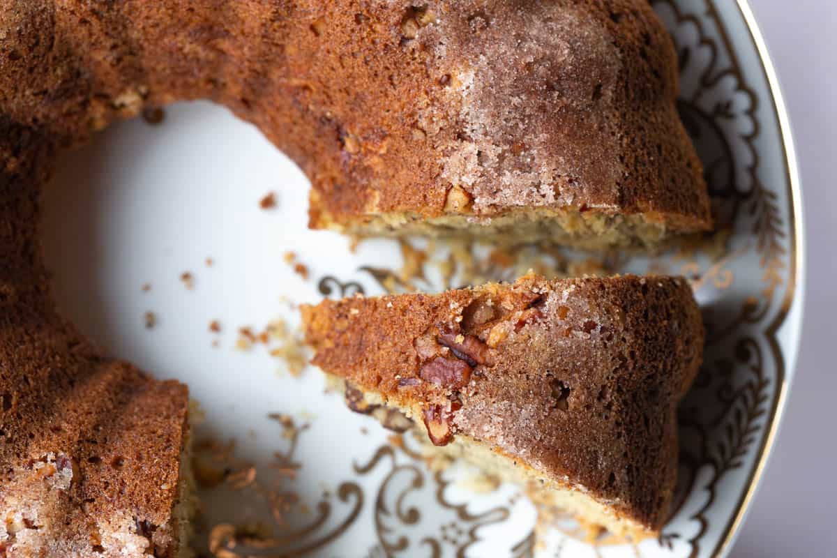 banana coffee cake on a decorative plate, with a slice cut out.