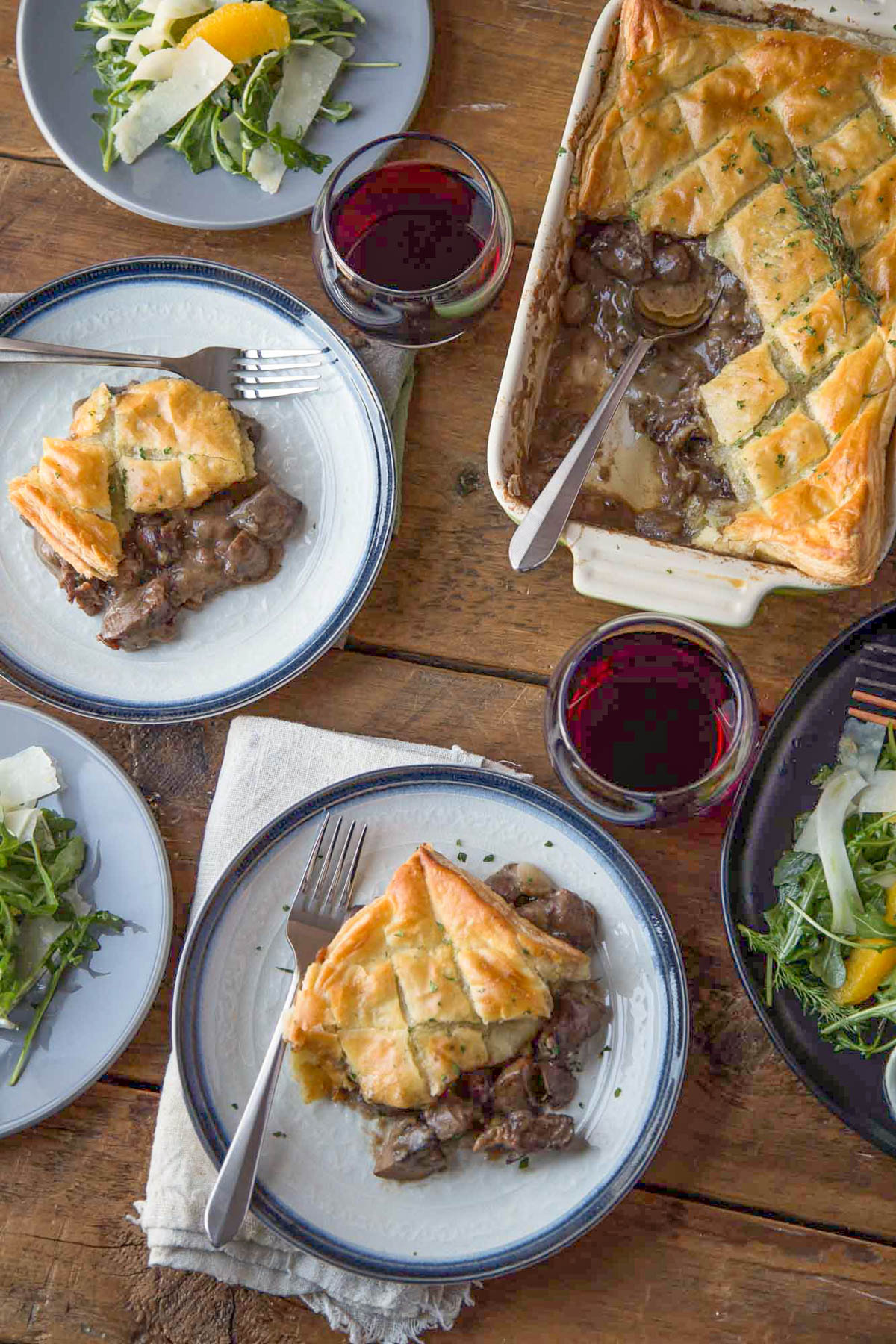 table set for dinner with beef wellington pot pie and arugula and fennel salad.