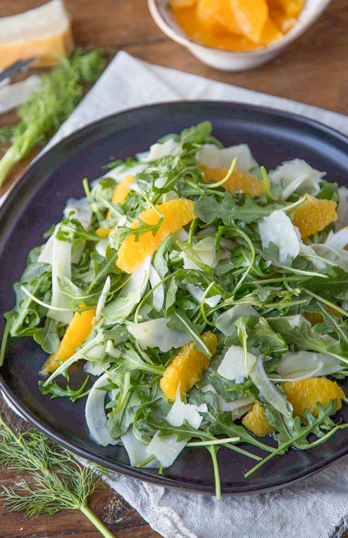 fennel and orange salad with arugula and shaved parmesan on a black plate.