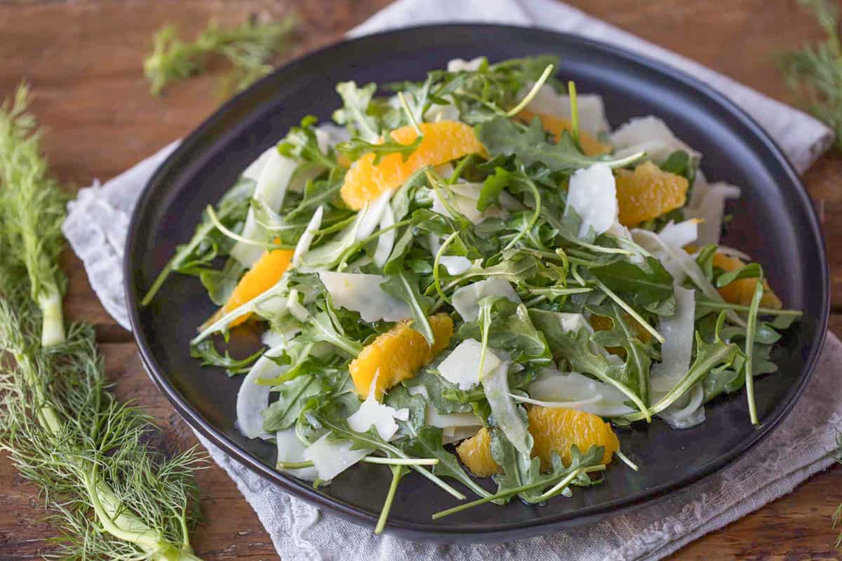 fennel, arugula, shaved parmesan, and segmented oranges on a black plate.