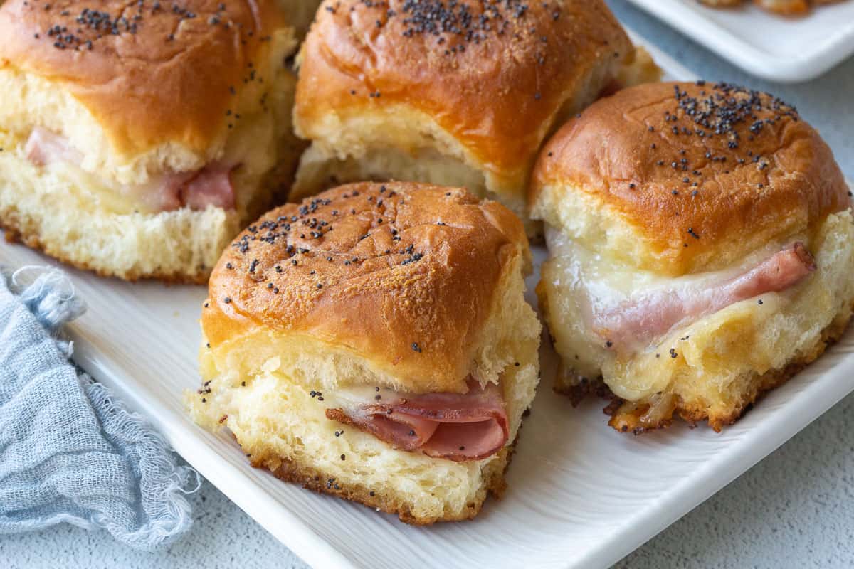 ham and swiss cheese sliders on a white serving platter.