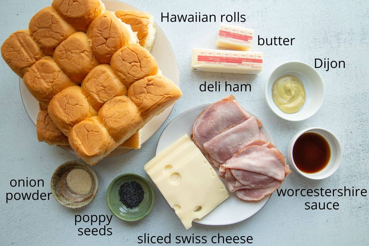 hawaiian rolls, ham, swiss, butter, and other ingredients on a white table.