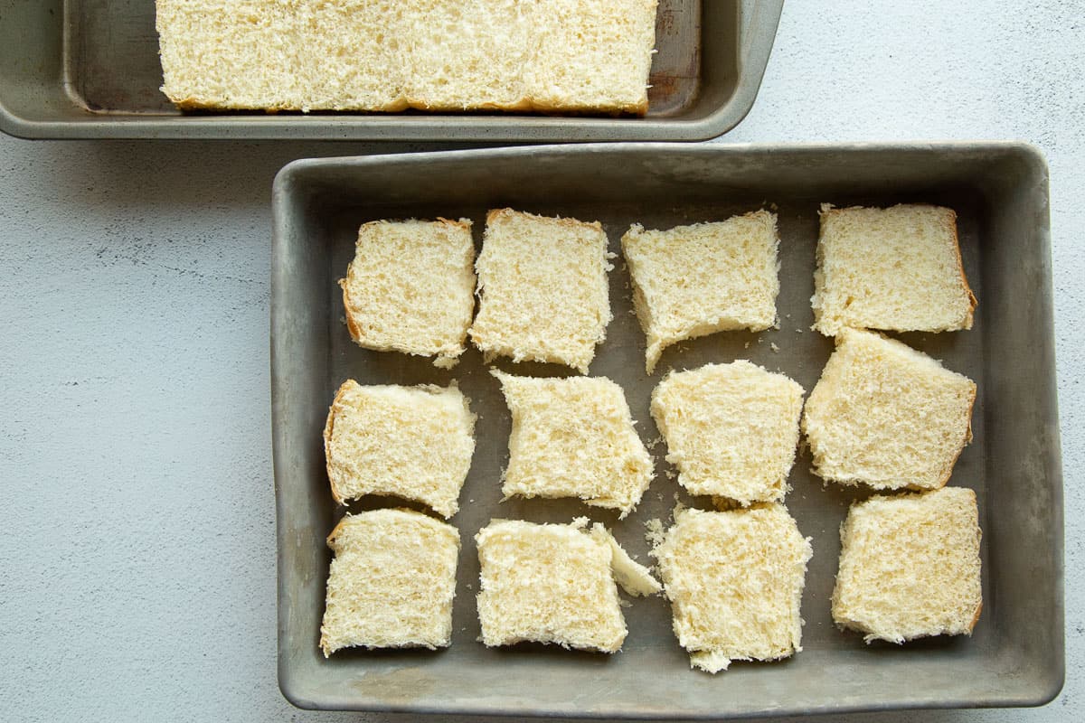 the bottom half of 12 hawaiian rolls in a metal baking dish.