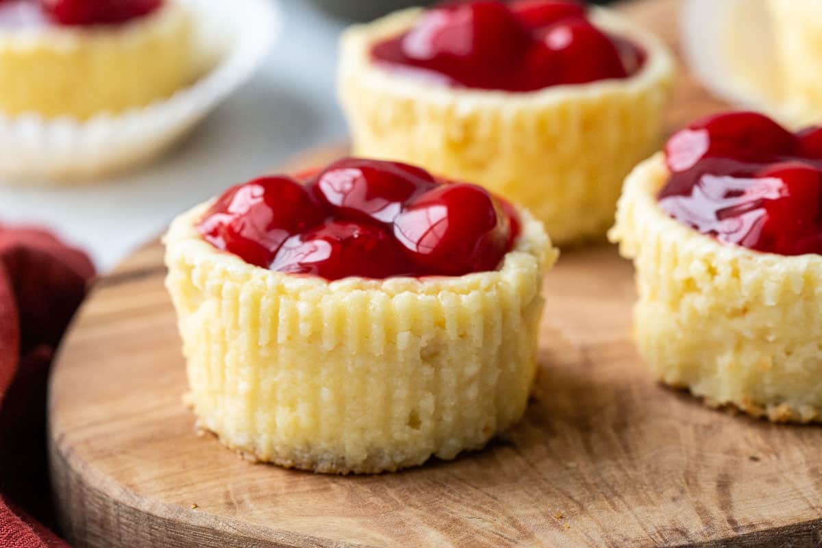mini cherry cheesecakes on a wooden board.