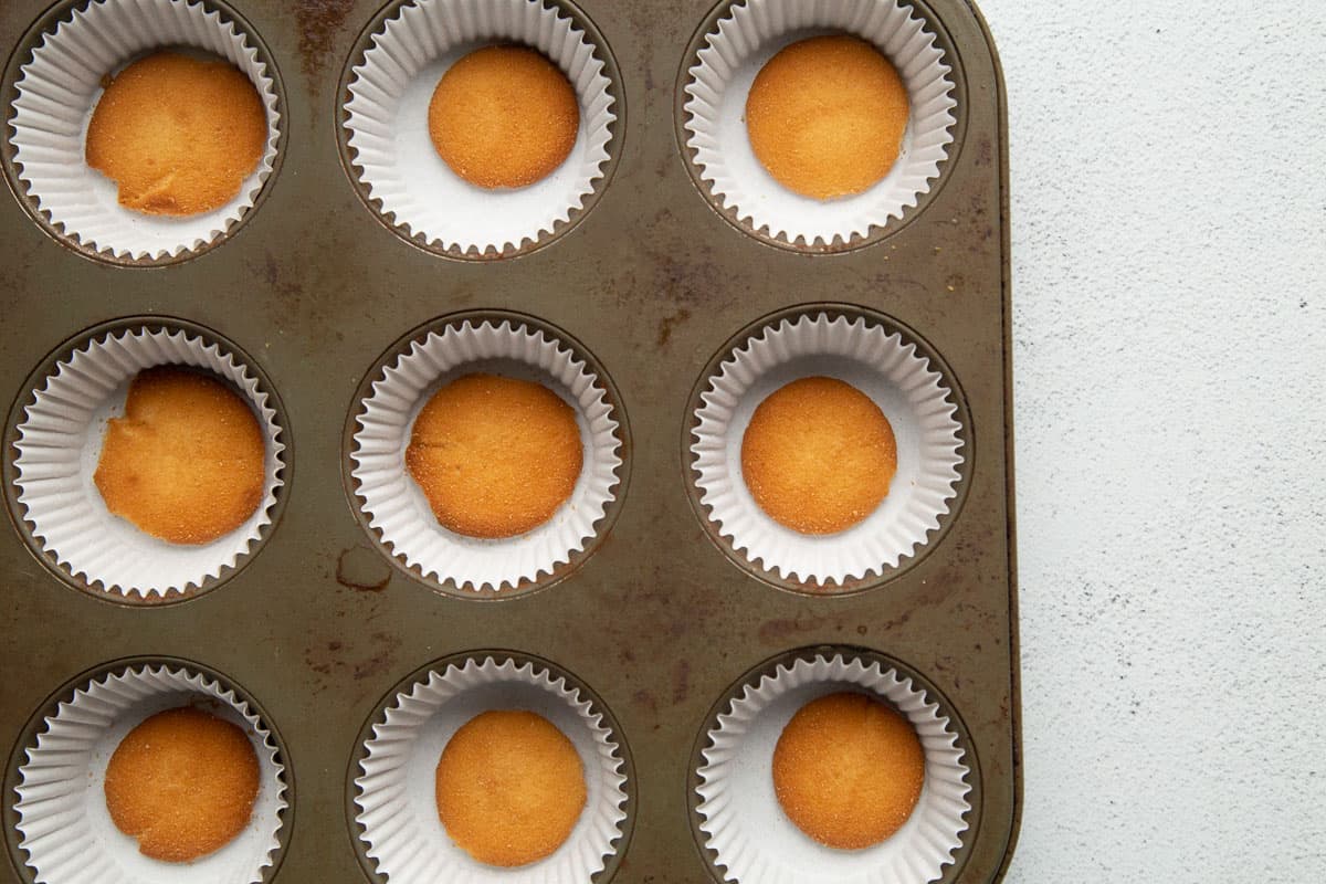 vanilla wafers in cupcake liners in a 12-cup muffin tin.
