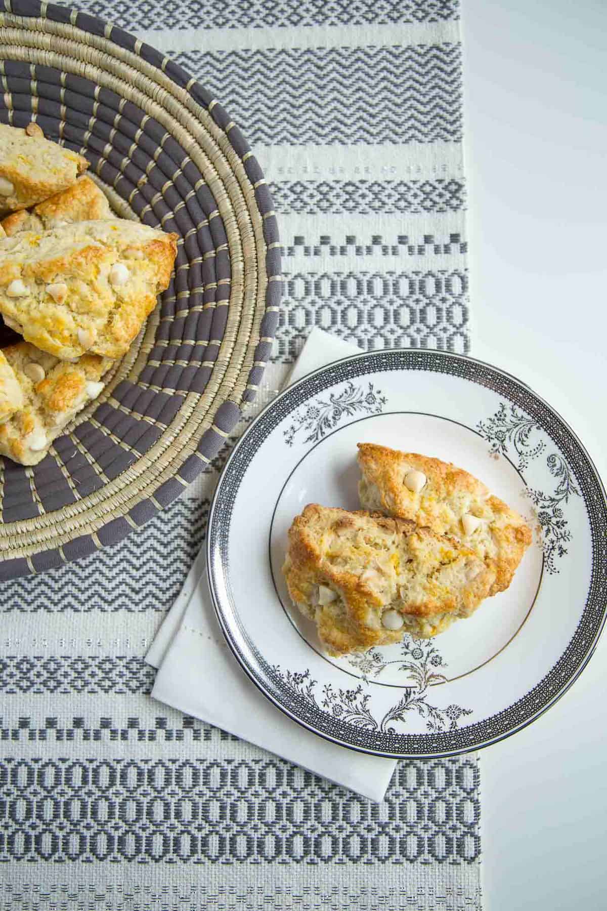 orange scones on a decorative gray plate and in a woven basket.