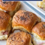 ham and cheese mini sandwiches on hawaiian rolls, topped with poppy seeds, on a white platter.