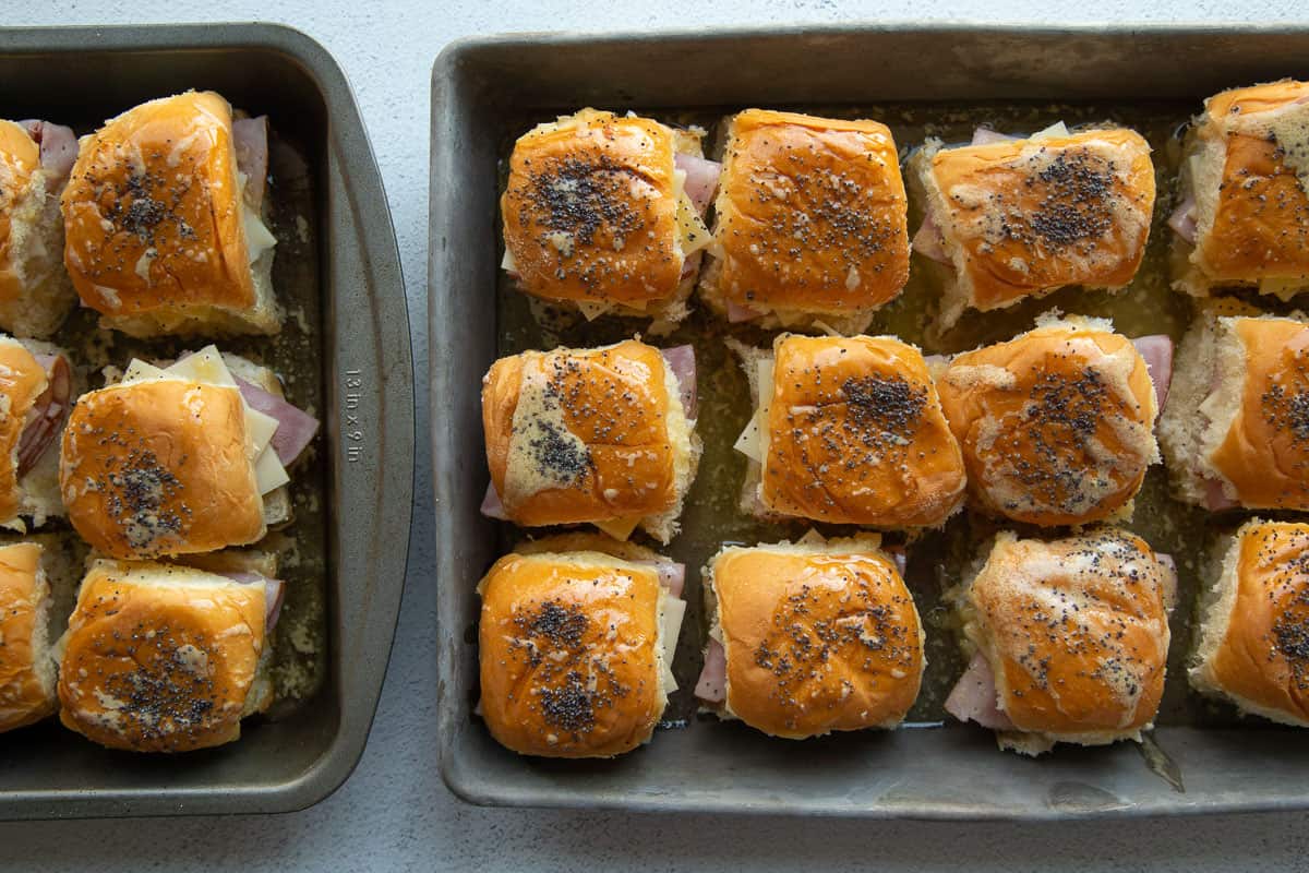 mini sandwiches topped with poppy seeds in a metal pan.