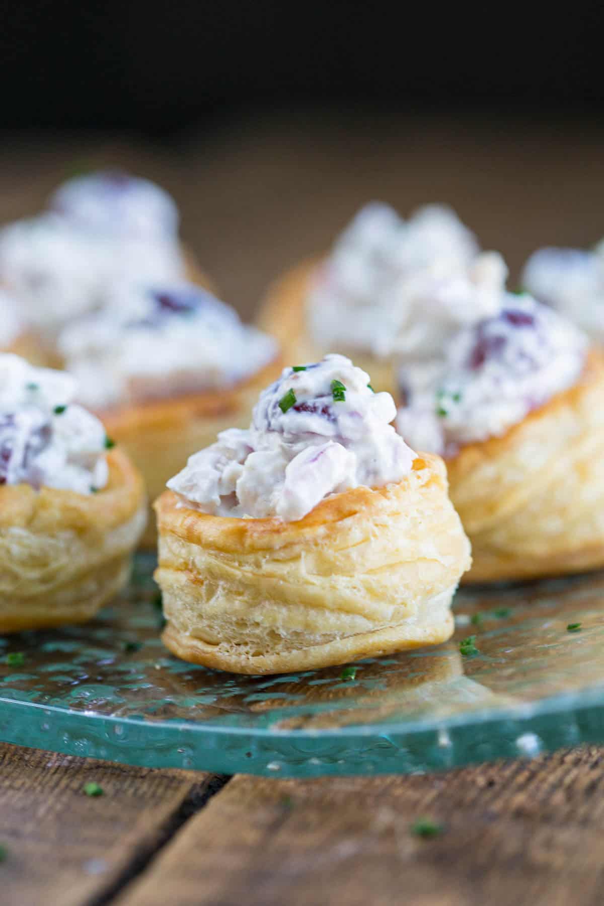puff pastry appetizers on a glass platter, stuffed with chicken salad.