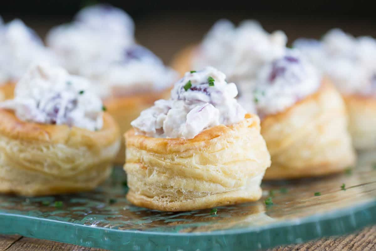 puff pastry cups filled with chicken salad on a glass platter.