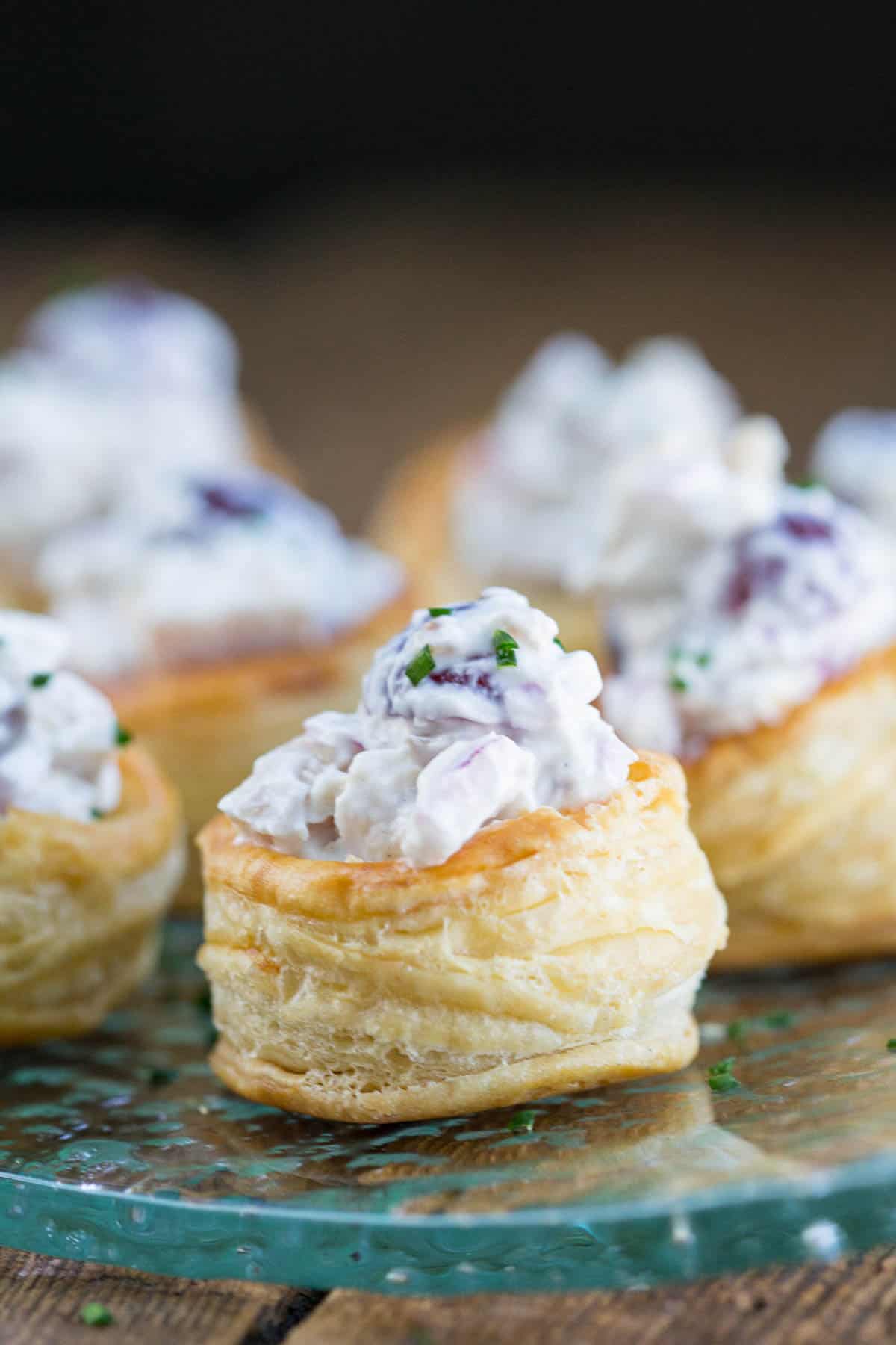 chicken salad inside homemade puff pastry cups on a glass platter.