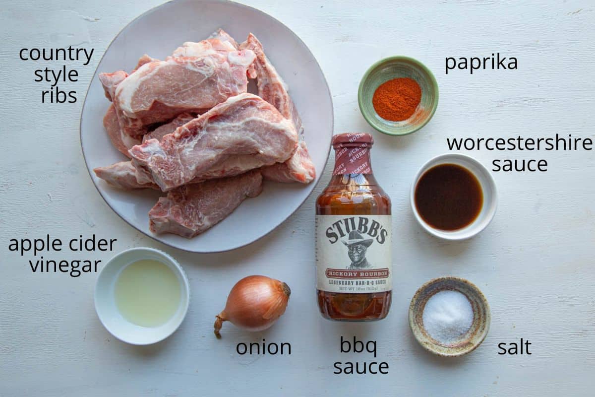 country style ribs, bbq sauce, onion, and other ingredients on a white table.