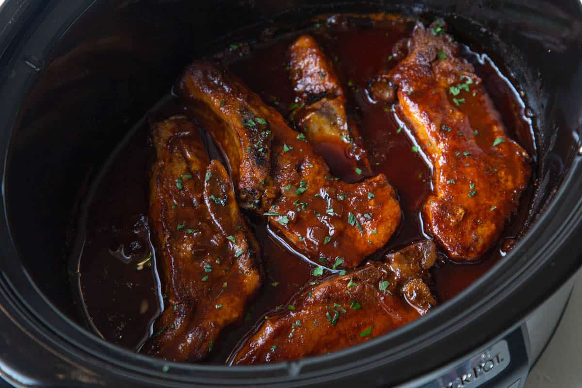 country style ribs in the slow cooker, covered in bbq sauce.