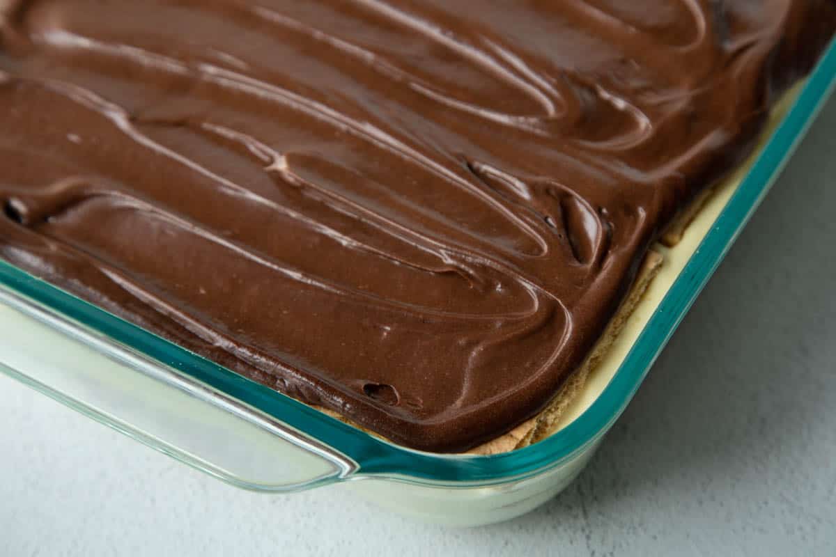 chocolate eclair cake topped with chocolate frosting in a glass casserole dish.