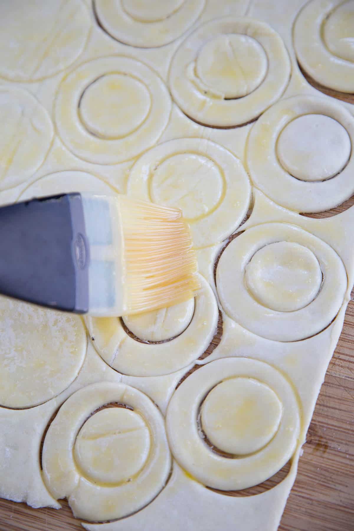 pastry brush brushing egg on top of puff pastry.