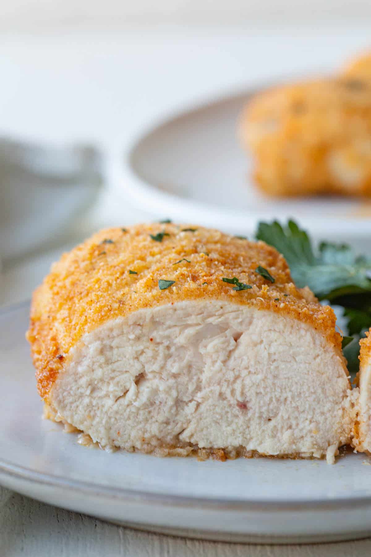 the interior of a baked parmesan chicken breast on a white plate.