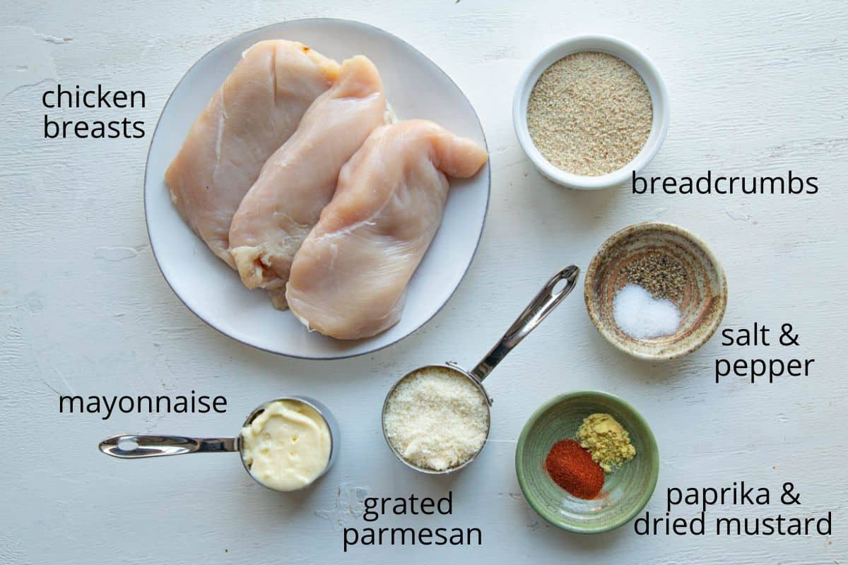 chicken, parmesan, breadcrumbs, and seasonings on a white table.