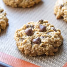 peanut butter oatmeal cookie with chocolate chips on a silicone baking mat.