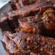 country style ribs coated in bbq sauce on a white platter.