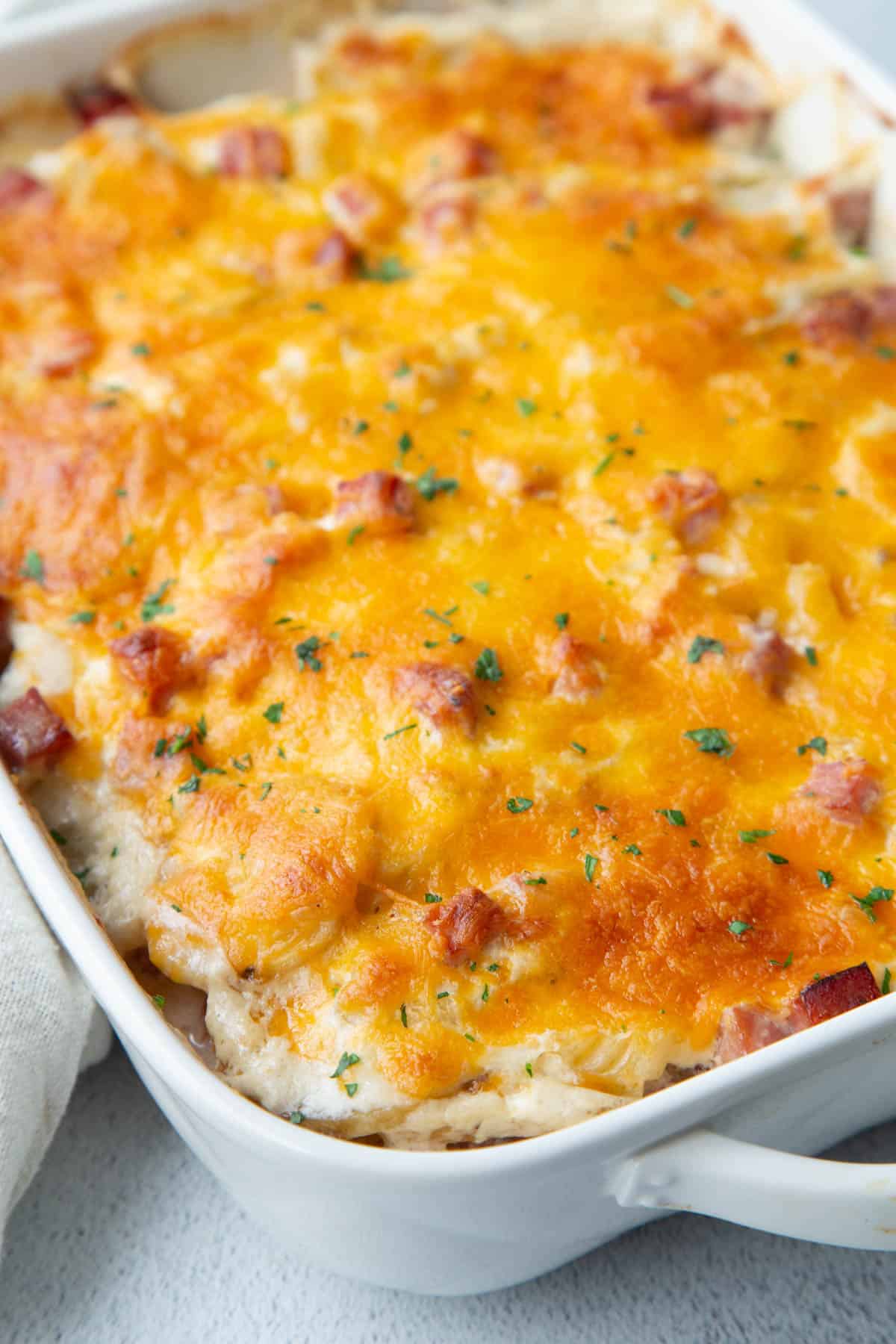 scalloped potatoes topped with cheese in a white casserole dish.