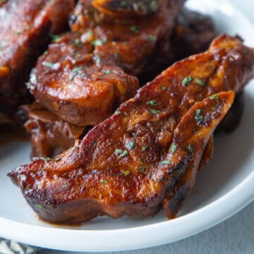country style ribs coated in bbq sauce on a white platter.