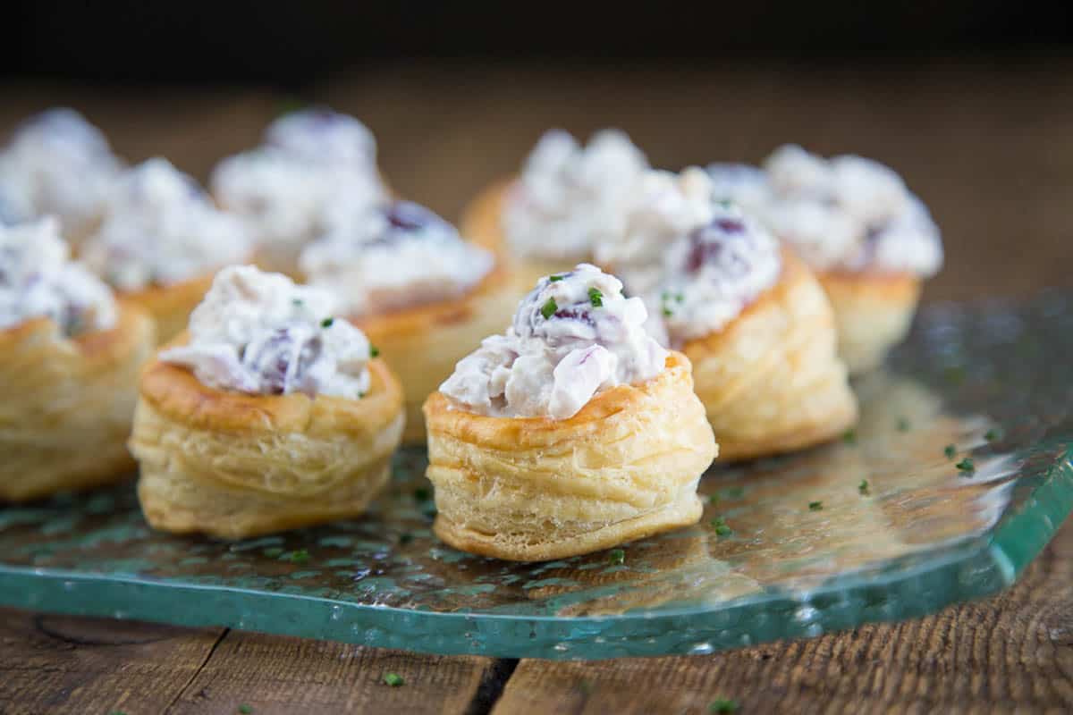 puff pastry cups filled with chicken salad on a glass platter.