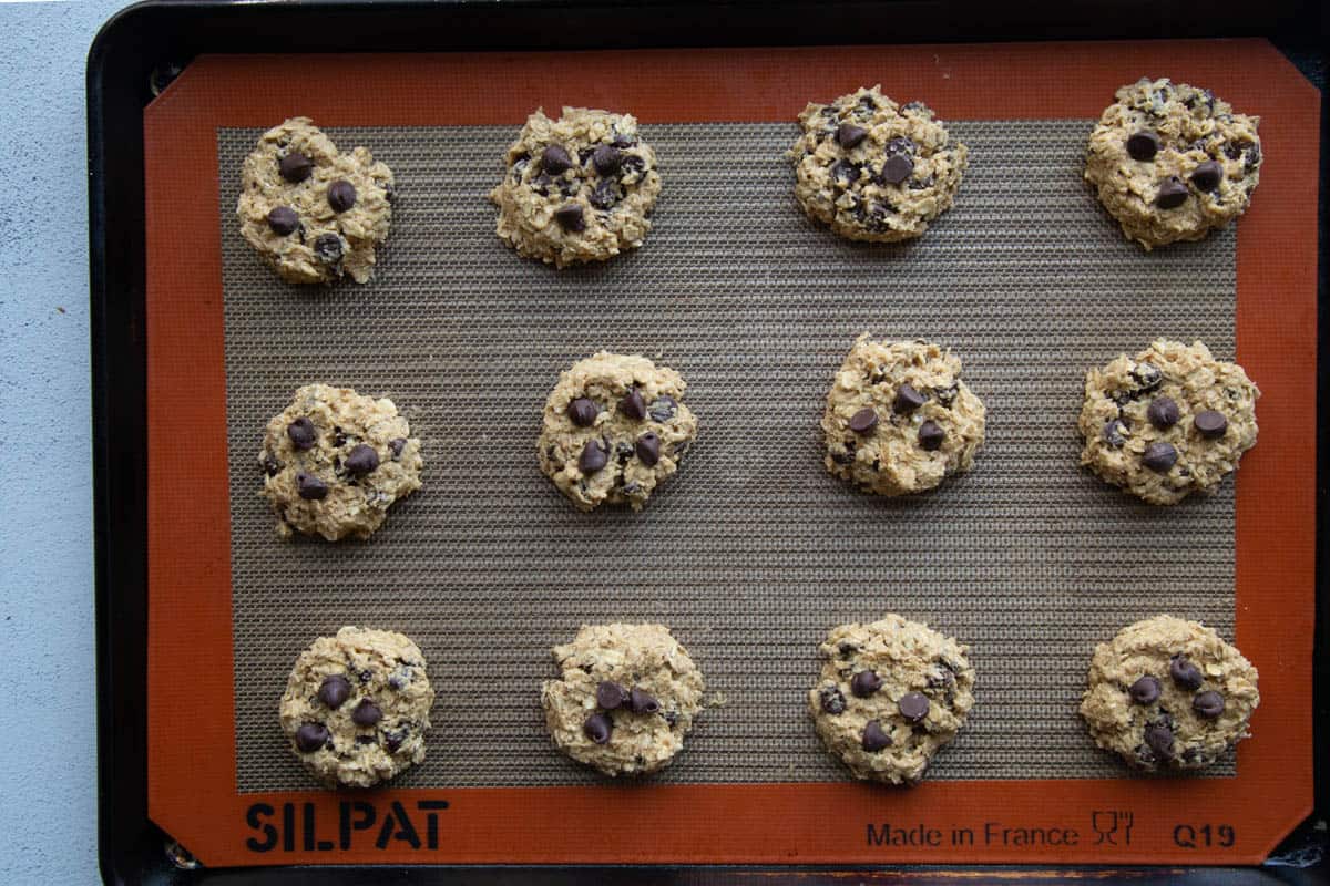 raw cookie dough topped with chocolate chips on a sheet pan.