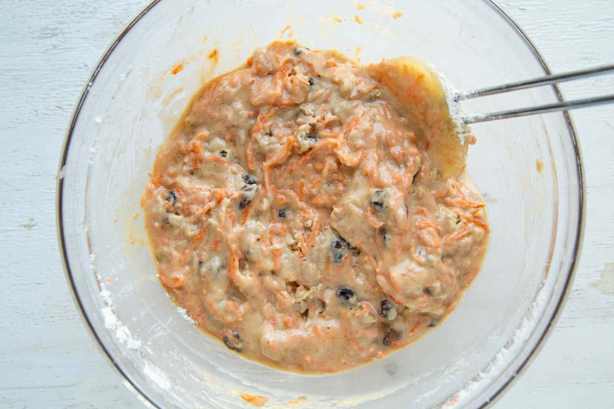 carrot muffin batter in a glass bowl with a spatula.