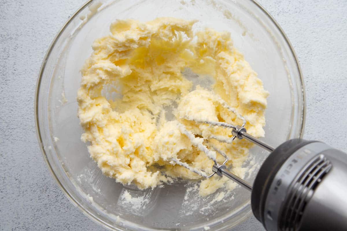 hand mixer creaming butter and sugar in a glass bowl.