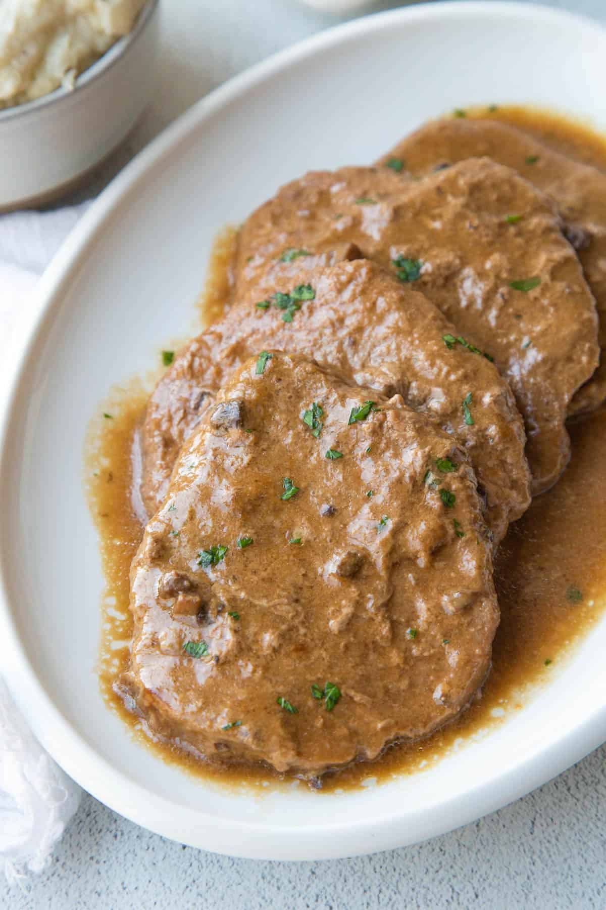 cube steaks in brown gravy on a white oval platter.