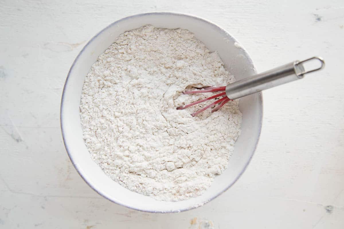 flour mixture in a low white bowl with a red whisk.