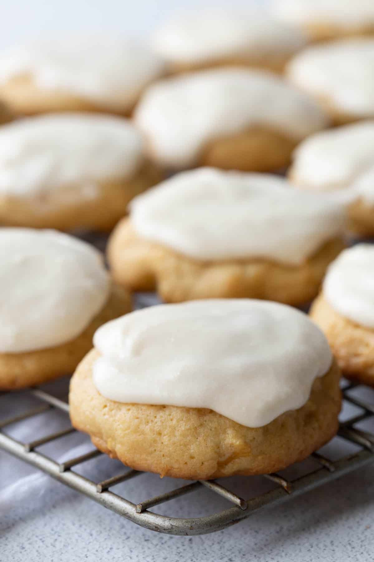 soft round pineapple cookies on a wire rack, topped with vanilla frosting.