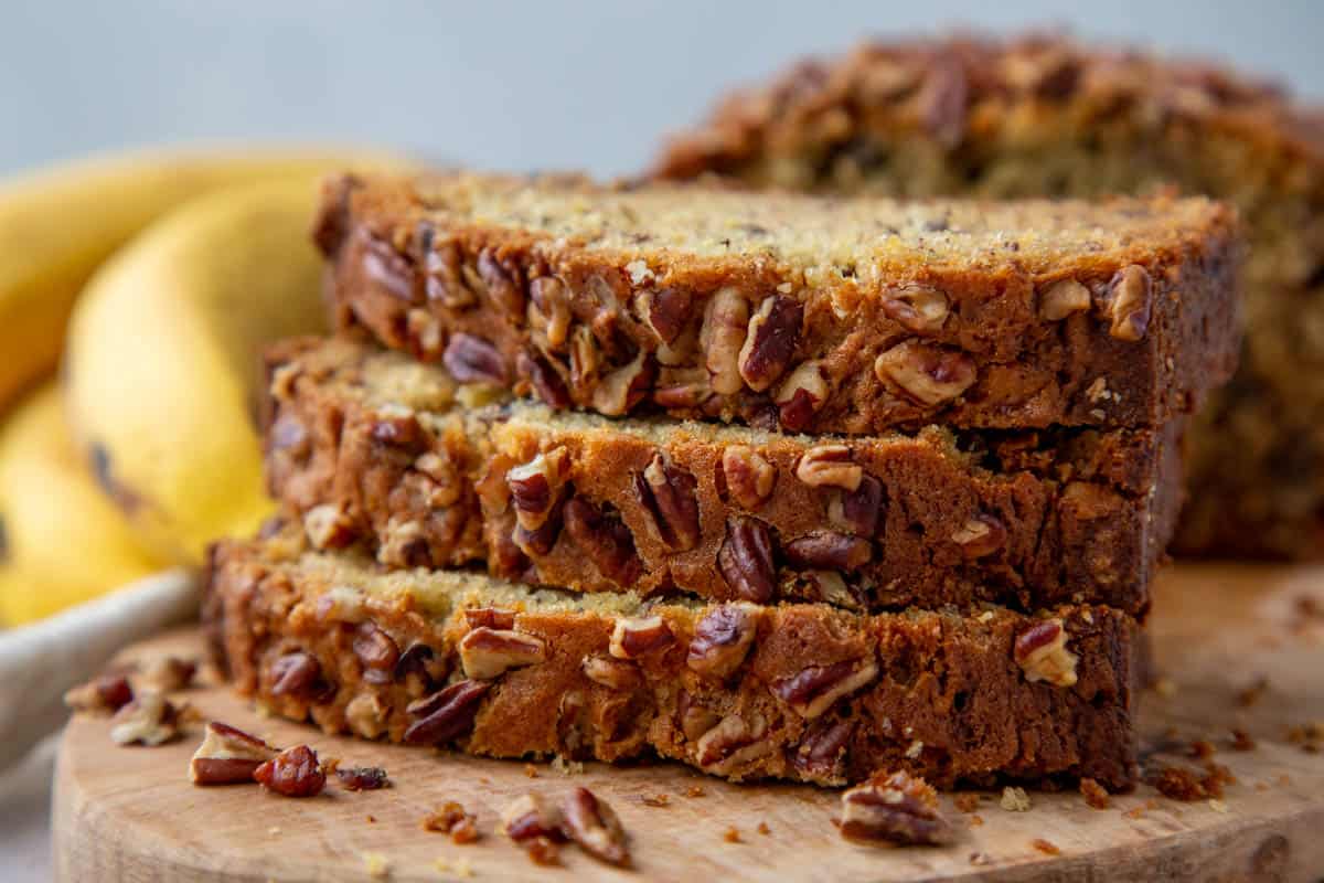 three slices of banana bread stacked on top of each other on a wooden serving board.