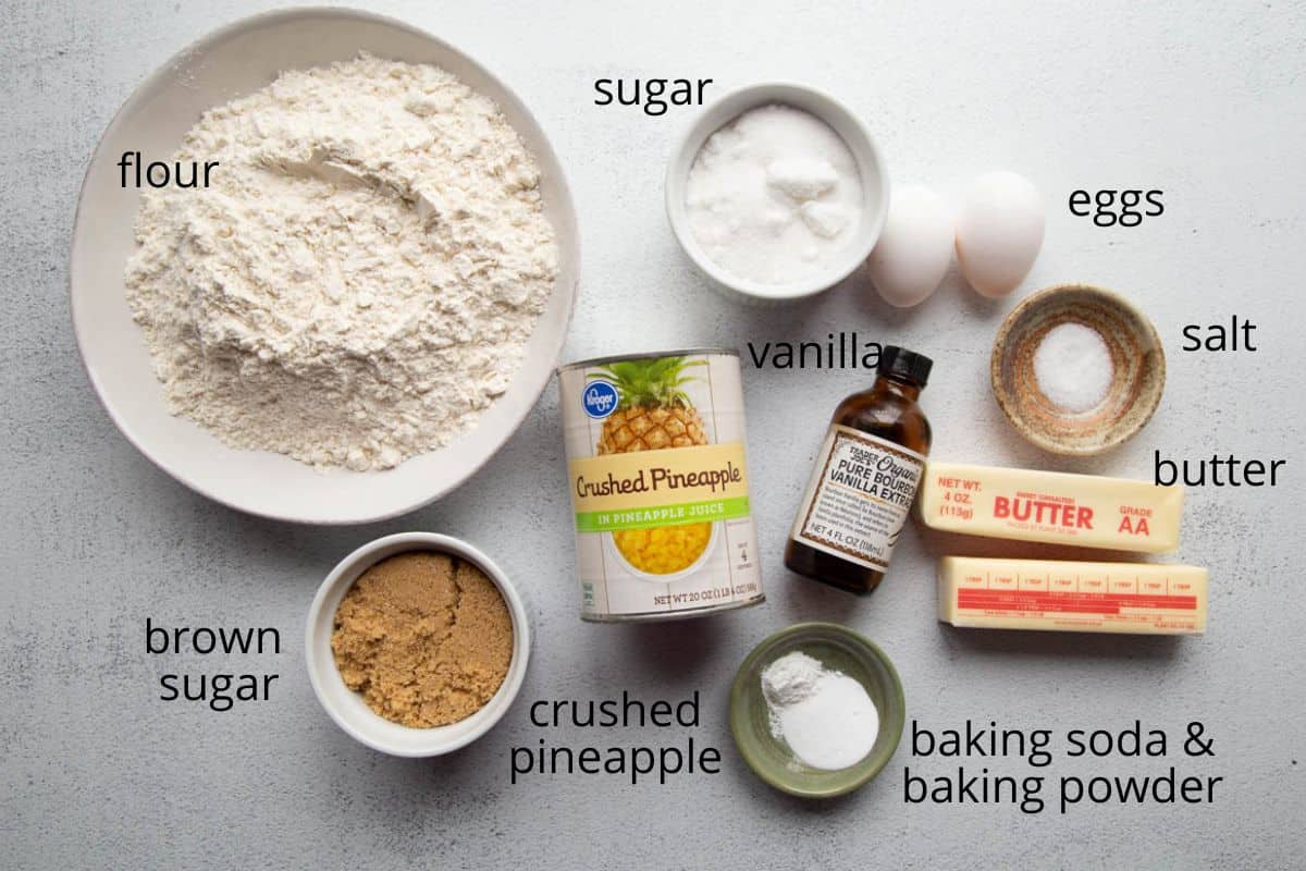 flour, sugar, crushed pineapple, and other ingredients labeled on a white table.