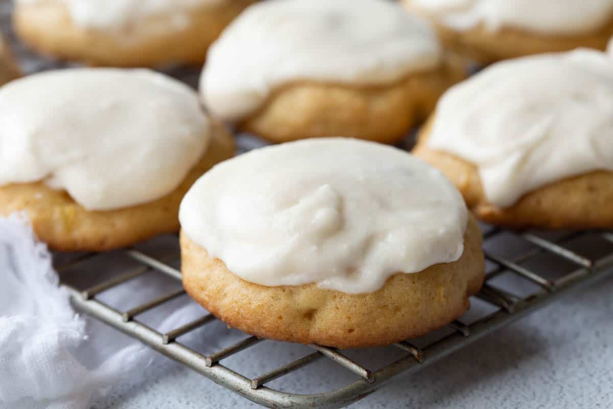 soft pineapple cookies on a wire rack, topped with vanilla frosting.