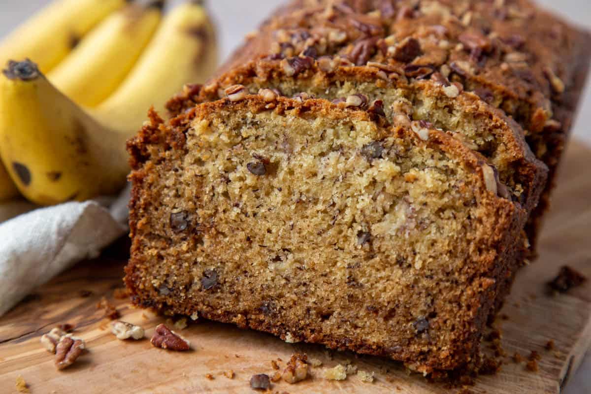 slices of banana pecan bread on a wooden serving board.