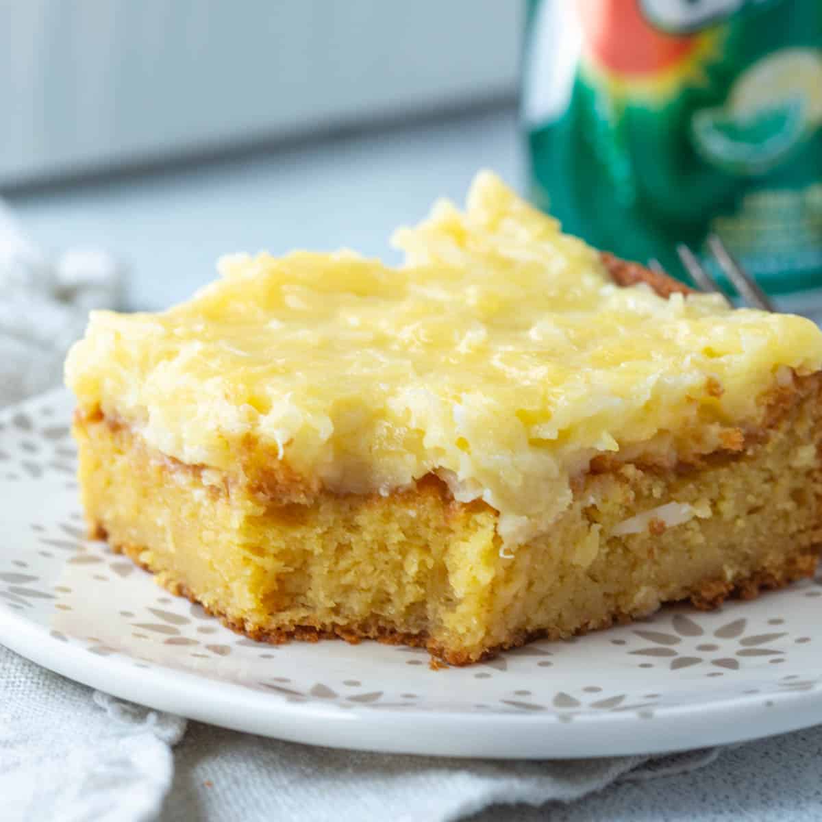 slice of 7up cake topped with a coconut frosting next to a can of 7up.