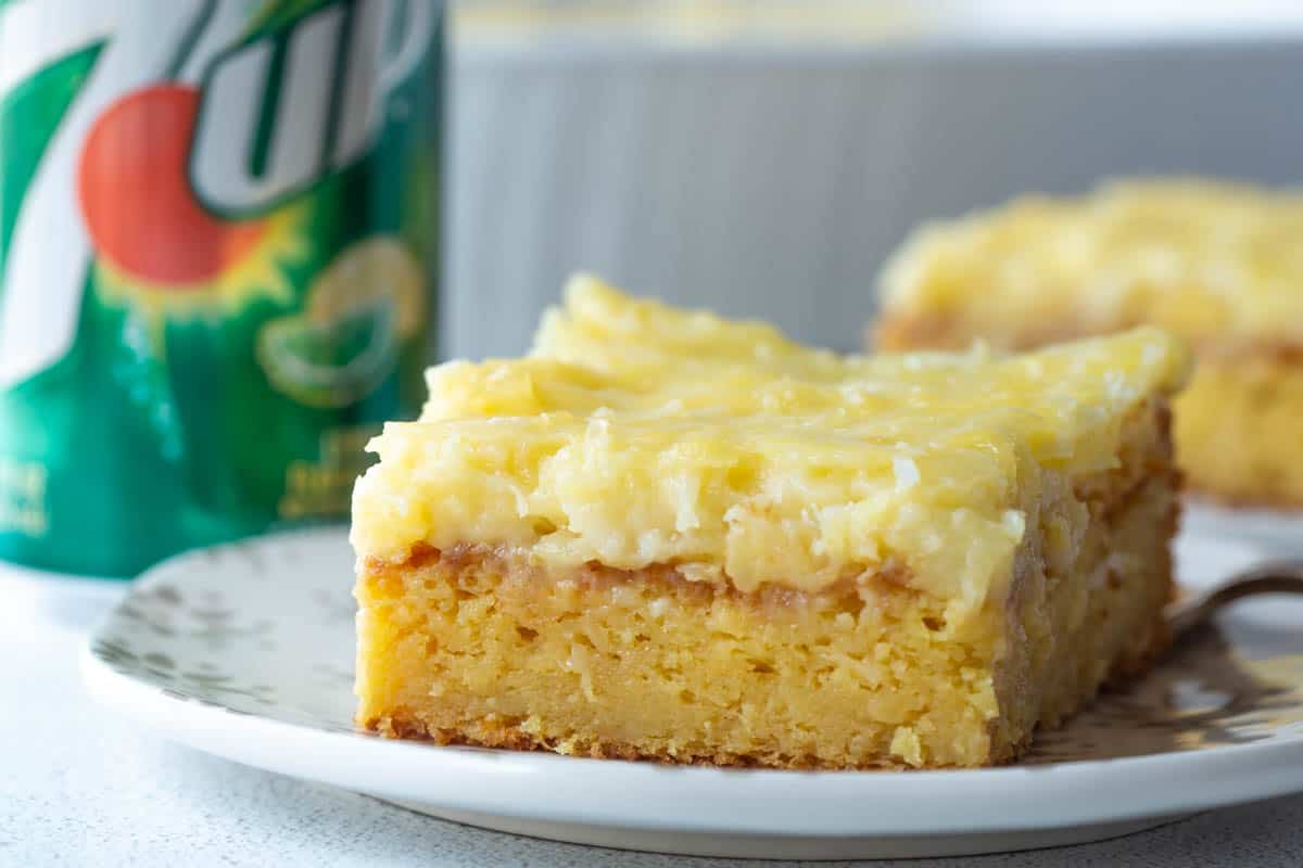 slice of 7up cake on a white plate, next to a can of 7up.