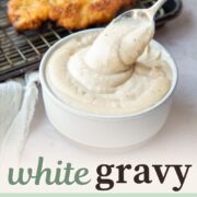 white gravy in a bowl, being lifted with a spoon.