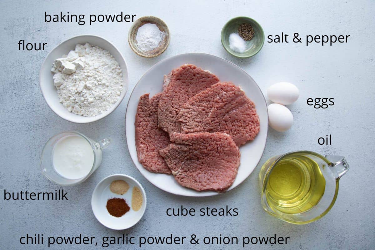 cube steaks, flour, oil, and other ingredients on a white table.