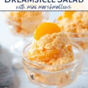 orange dreamsicle salad piled into glass parfait dishes, topped with mandarin oranges and surrounded by mini marshmallows.
