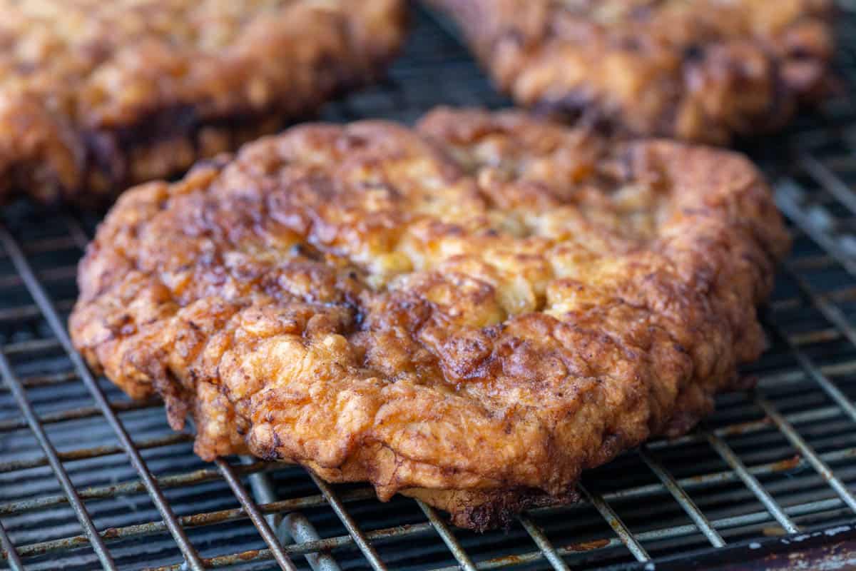 freshly cooked chicken fried steak on a wire rack.