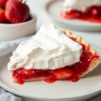 slice of strawberry jello pie topped with whipped topping on a white plate.