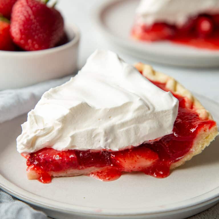 slice of strawberry jello pie topped with whipped topping on a white plate.