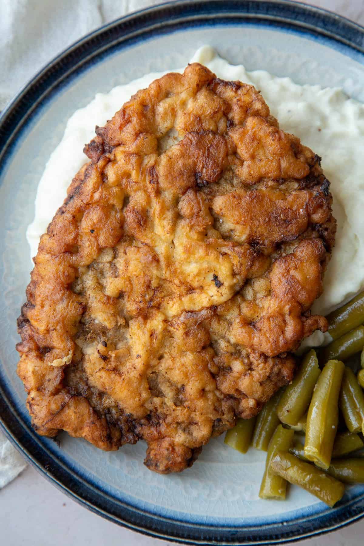 chicken fried steak on a bed of mashed potatoes.