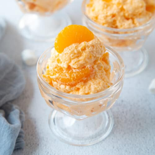 orange dreamsicle salad in glass parfait dishes, topped with mandarin oranges.
