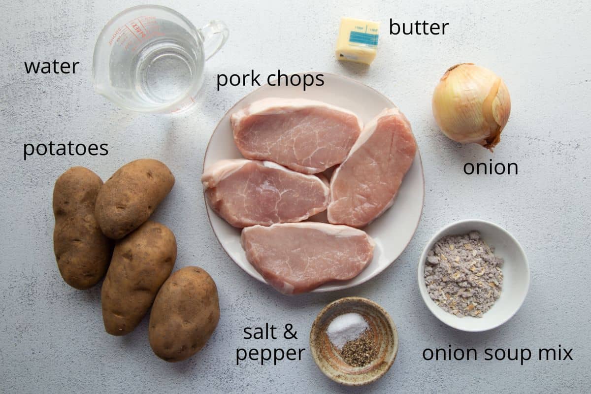 pork chops, potatoes, onion, and other ingredients on a white table.
